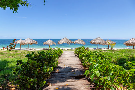 Beautiful view of a wooden path leading to the sandy beach on the Caribbean Sea in Cuba during a bright and sunny day.