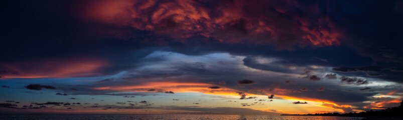 Naklejka na ściany i meble Dramatic Panoramic View of a cloudscape during a dark and colorful sunset. Taken over Beach Ancon in Trinidad, Cuba.