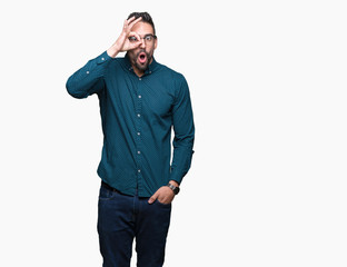 Fototapeta premium Young handsome business man wearing glasses over isolated background doing ok gesture shocked with surprised face, eye looking through fingers. Unbelieving expression.