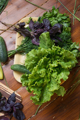 cooking green  salad from fresh organic vegetables, basilic and dill at wooden table. flat lay