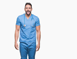 Fototapeta premium Handsome young doctor surgeon man over isolated background sticking tongue out happy with funny expression. Emotion concept.