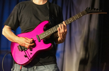Obraz na płótnie Canvas Musician playing pink electric guitar on stage .