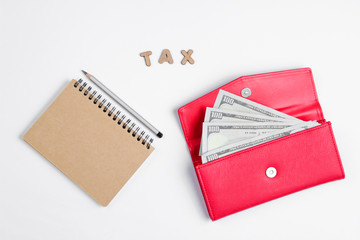 Creative business concept. Notebook, pencil, wallet with dollar bills on white background with the word tax of wooden letters, minimalism