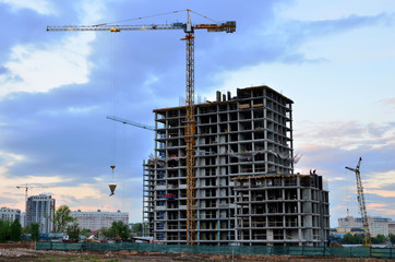 Fototapeta na wymiar Tower cranes at construction site in the sunset sky - Image