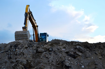 Heavy excavator working at construction site. Crushing and processing of rocks in the mining quarry. Production of building stone and crushed stone