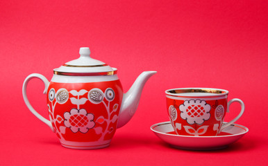 Retro ceramic cup and teapot on red background. Top view