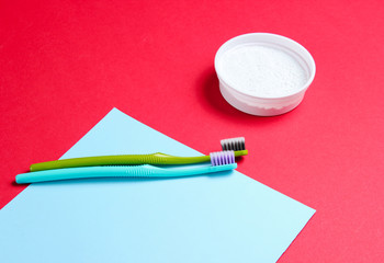 Two toothbrushes, tooth powder on red blue paper background. Minimalism oral hygiene concept