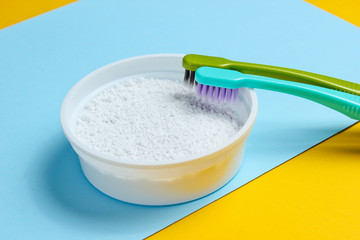 Two toothbrushes, tooth powder on yellow blue background. Minimalism oral hygiene concept.