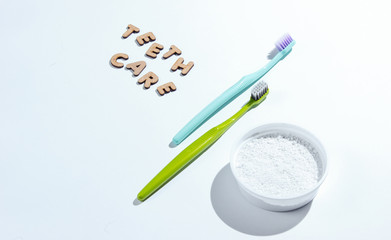 Two toothbrushes, tooth powder on white background with slogan teeth care. Minimalism oral hygiene...