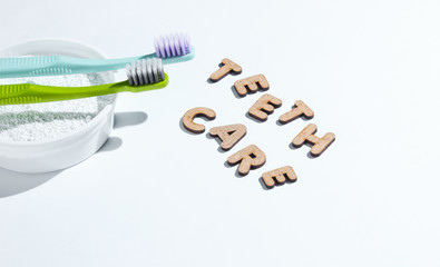 Two toothbrushes, tooth powder on white background with slogan teeth care. Minimalism oral hygiene concept.