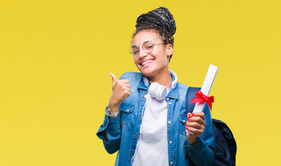 Young braided hair african american student girl holding degree over isolated background happy with big smile doing ok sign, thumb up with fingers, excellent sign - obrazy, fototapety, plakaty