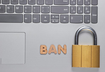 Ban account. Lock on laptop keyboard with the word ban of wooden letters © splitov27