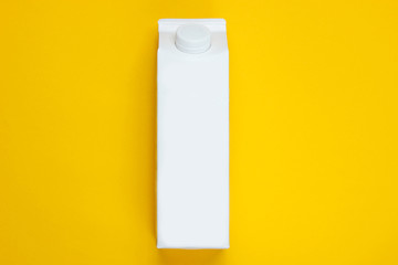 White cardboard box of yogurt on a yellow background. Minimalistic eco food concept