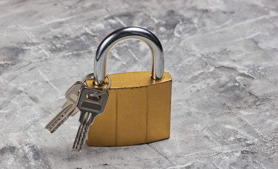 Metal lock with keys on gray concrete background.