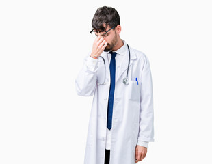 Young doctor man wearing hospital coat over isolated background tired rubbing nose and eyes feeling fatigue and headache. Stress and frustration concept.