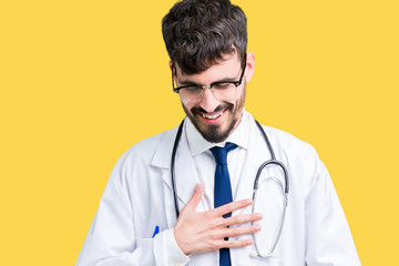 Young doctor man wearing hospital coat over isolated background Smiling and laughing hard out loud because funny crazy joke. Happy expression.