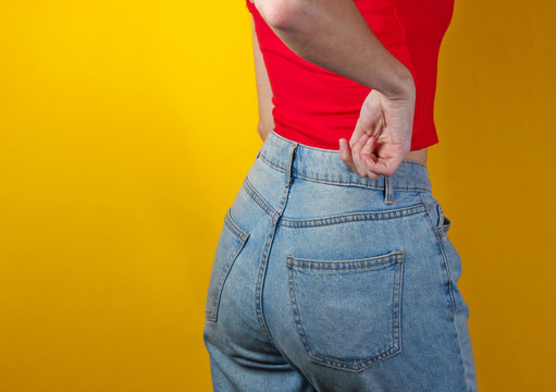 Woman in blue jeans on a yellow background. Back view. Studio shot