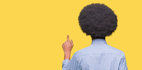 Young african american business man with afro hair wearing glasses Posing backwards pointing behind with finger hand