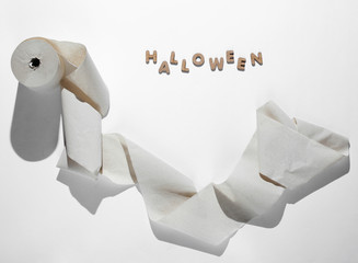 Halloween minimal concept. A roll of toilet paper on white background with the word halloween.