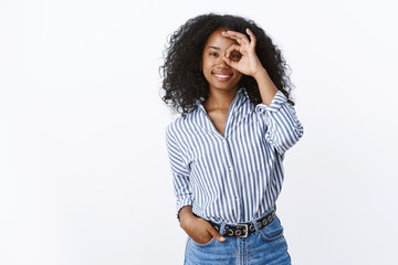 Optimistic charming african-american young 25s woman wearing striped blouse showing okay ok gesture...