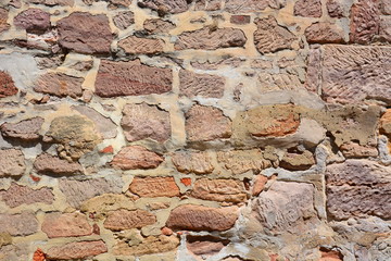 medieval wall made of red and brown irregular stones with mortar - background
