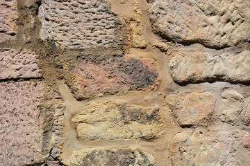 medieval wall made of red and brown irregular stones with mortar - background
