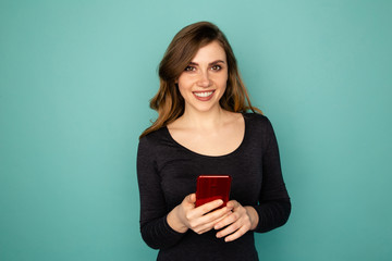 Cute female holding mobile and smiling isolated over the blue background