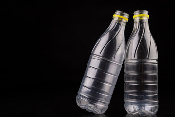 Plastic bottle after a food drink. Disposable packaging on a dark table. Black background.