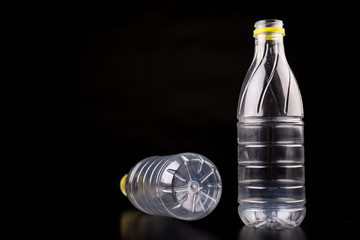 Plastic bottle after a food drink. Disposable packaging on a dark table. Black background.