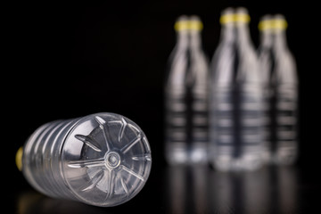 Plastic bottle after a food drink. Disposable packaging on a dark table. Black background.