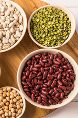 Top view of assortment of peas, lentils, beans and legumes over white wooden background.