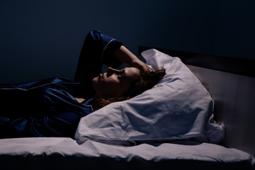 Sad alone woman lying the bed. Insomnia concept - obrazy, fototapety, plakaty