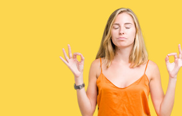 Beautiful young woman wearing orange shirt over isolated background relax and smiling with eyes closed doing meditation gesture with fingers. Yoga concept.