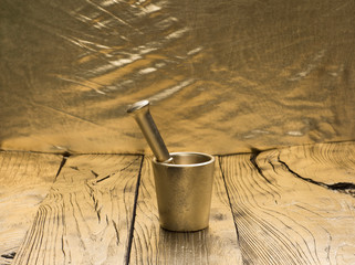 Vintage gold mortar with pestle on golden wooden background