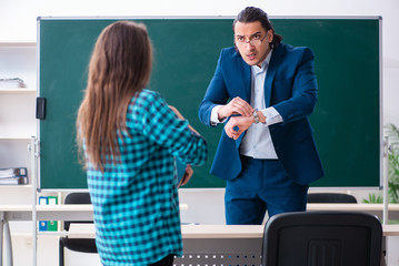 Young handsome teacher and female student in the classroom 