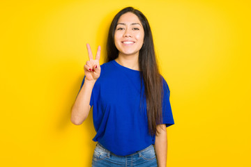 Beautiful brunette woman wearing blue t-shirt over yellow isolated background smiling with happy...