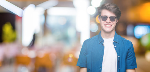 Fototapeta na wymiar Young handsome man wearing sunglasses over isolated background with a happy and cool smile on face. Lucky person.