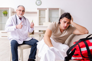 Old male doctor visiting young male patient  