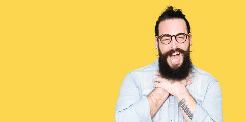 Obraz premium Young hipster man with long hair and beard wearing glasses shouting and suffocate because painful strangle. Health problem. Asphyxiate and suicide concept.