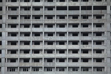 The fragment of the facade of unfinished and abandoned monolithic residential building. Windows of the multi-storey building