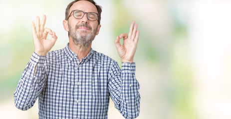Handsome middle age elegant senior business man wearing glasses over isolated background relax and smiling with eyes closed doing meditation gesture with fingers. Yoga concept.