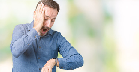 Handsome middle age elegant senior man over isolated background Looking at the watch time worried, afraid of getting late