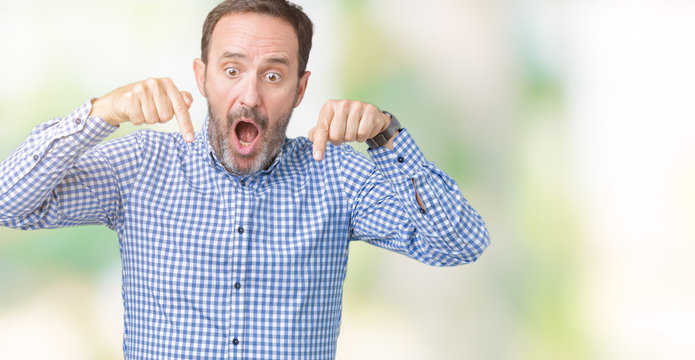 Handsome middle age elegant senior man over isolated background Pointing down with fingers showing advertisement, surprised face and open mouth