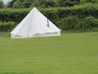 A White Canvas Bell Tent with a Metal Stove Chimney.