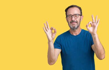 Handsome middle age hoary senior man wearin glasses over isolated background relax and smiling with eyes closed doing meditation gesture with fingers. Yoga concept.