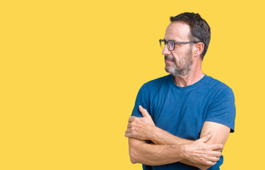 Fototapeta premium Handsome middle age hoary senior man wearin glasses over isolated background smiling looking to the side with arms crossed convinced and confident