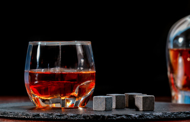 Glass of whiskey with black chilling cubes