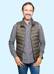 Middle age handsome man wearing winter vest with a happy and cool smile on face. Lucky person.