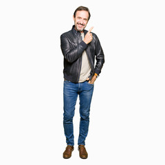 Fototapeta premium Middle age handsome man wearing black leather jacket cheerful with a smile of face pointing with hand and finger up to the side with happy and natural expression on face