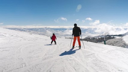 Tracking Shot As Father With His Daughter Skiing Down To Sightseeing Platform. Middle aged man and his daughter enjoy idyllic perfect weather as they are in ski mountains resort.